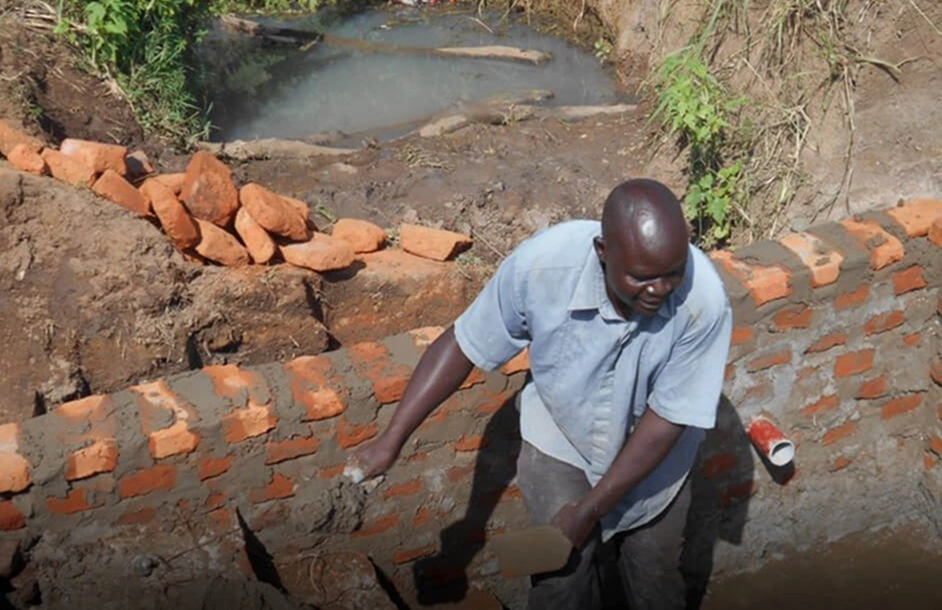 Worker building a community water well in Uganda