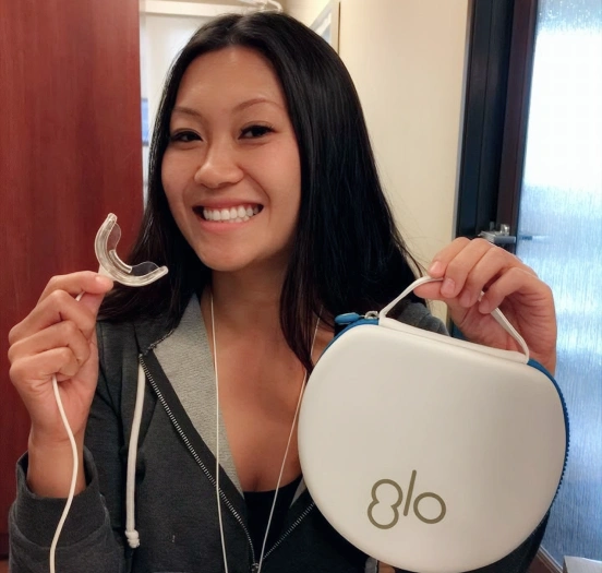 Patient holding GLO teeth whitening system