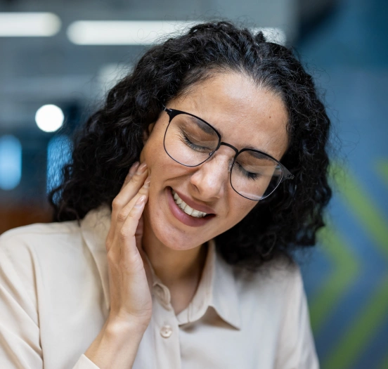 Woman experiencing jaw pain caused by a TMJ disorder